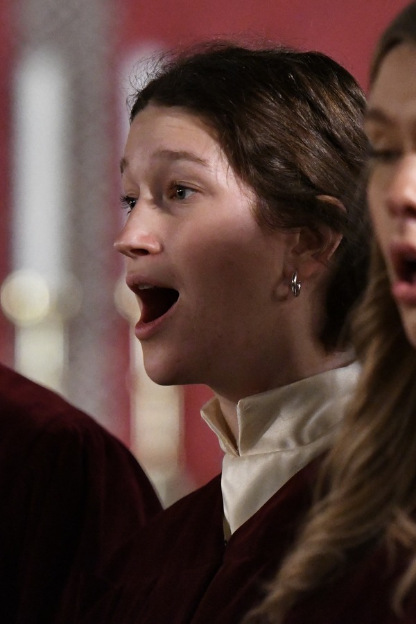 Two female students in choir performance robes hugging and smiling.